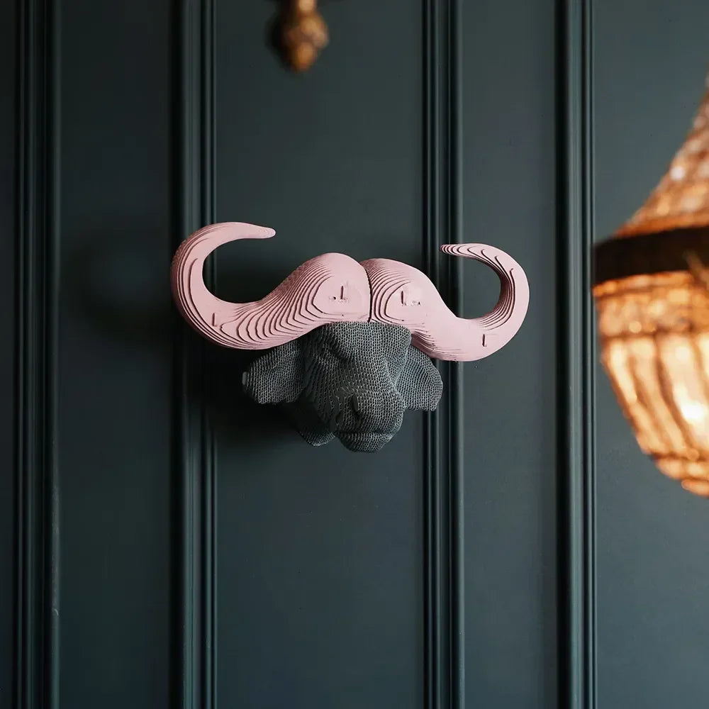 Wanddekoration in Form eines Büffelkopfes mit grauer Schnauze und rosa Hörnern aus geschichteten Materialien