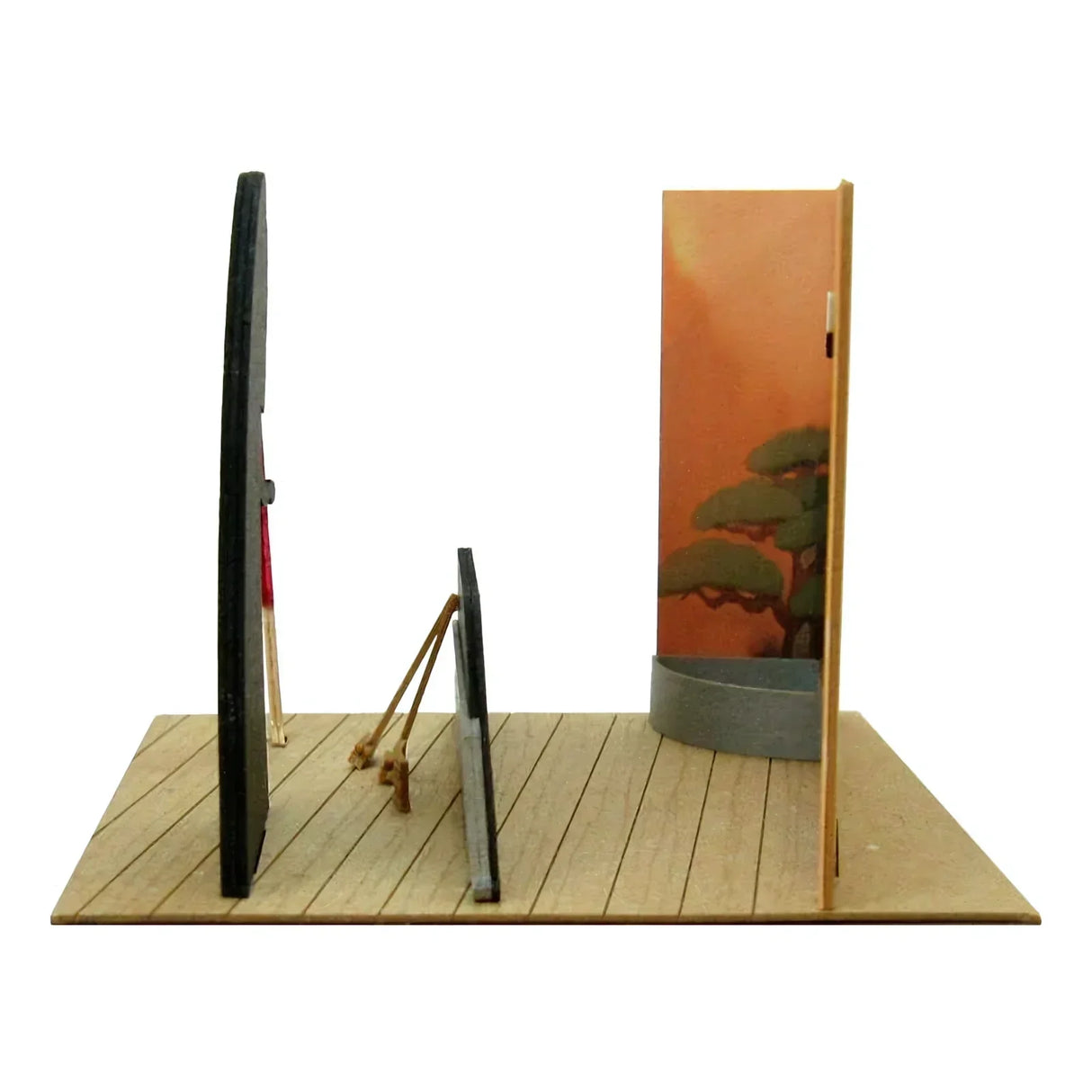 Miniatur-Diorama mit Holzboden, zwei schwarzen Wänden und einer orangefarbenen Wand mit Baumdesign