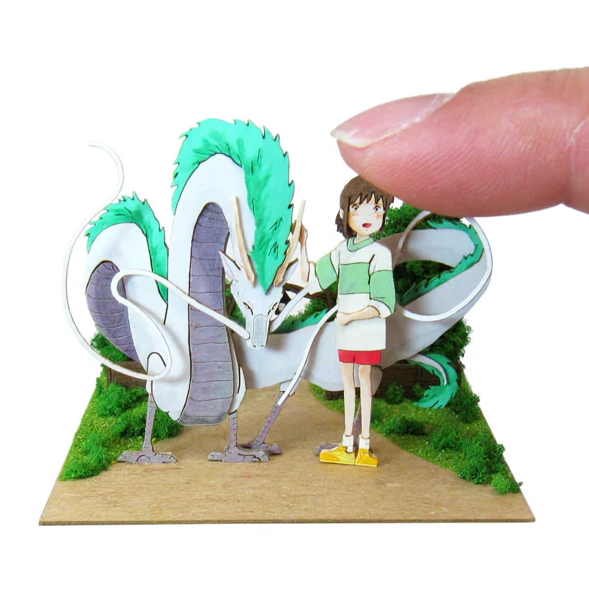 Finger berührt eine Papierfigur von Haku und Chihiro aus Spirited Away