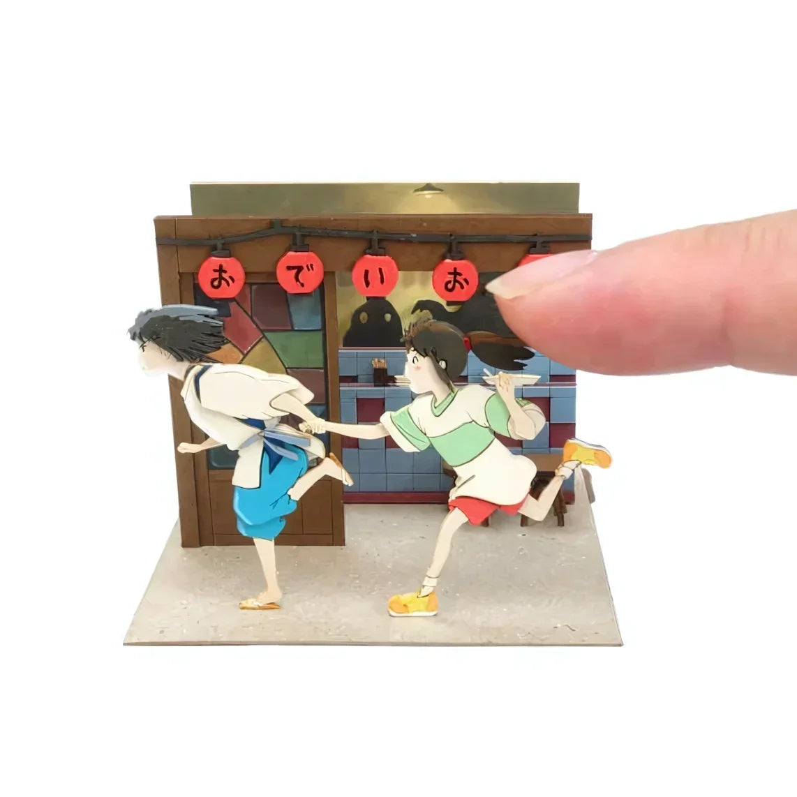 Finger berührt eine Anime-Szene mit zwei rennenden Figuren vor einem Gebäude mit roten Laternen