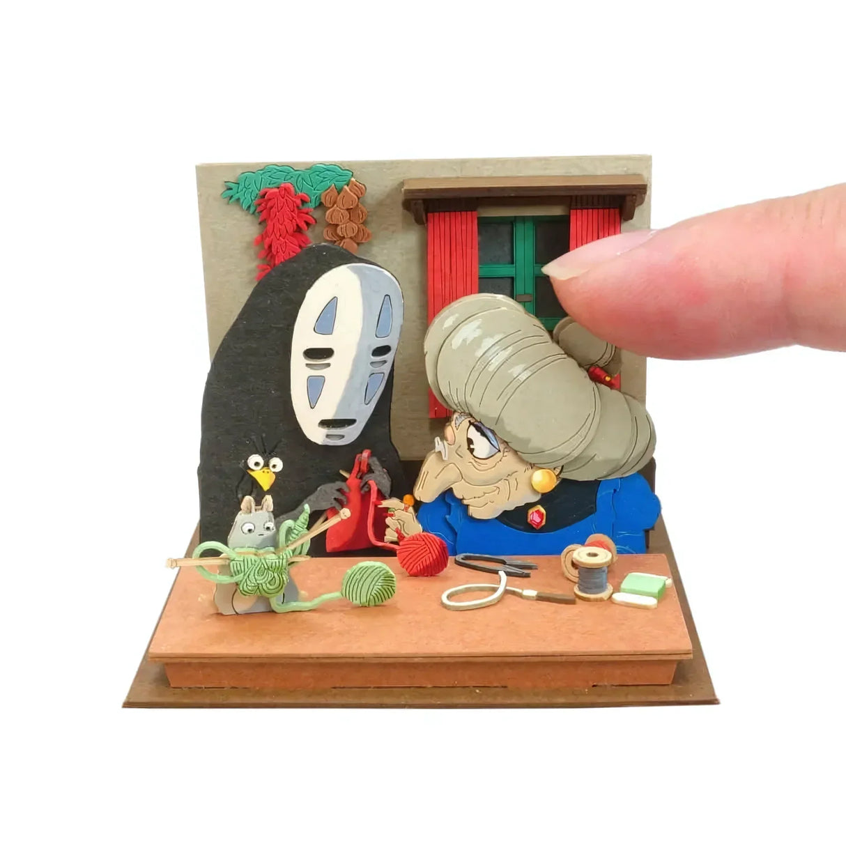 Eine Miniatur-Diorama-Szene mit Figuren aus Chihiros Reise ins Zauberland, die stricken