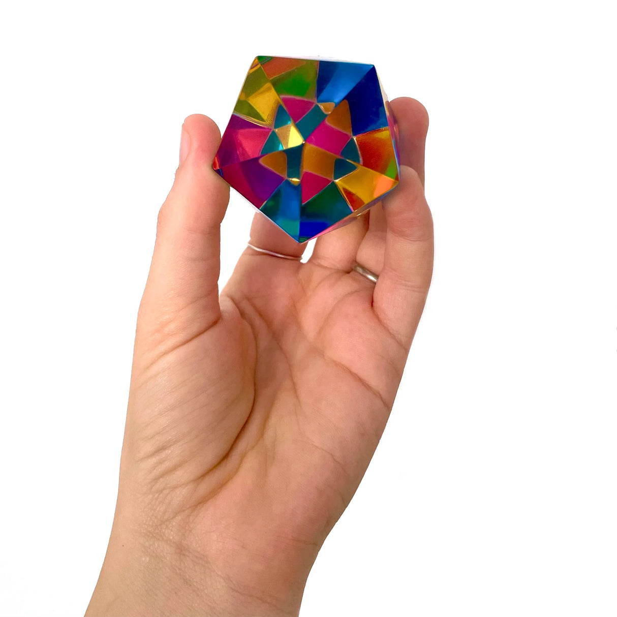 Hand hält ein Kaleidoskop mit bunten, reflektierenden Facetten