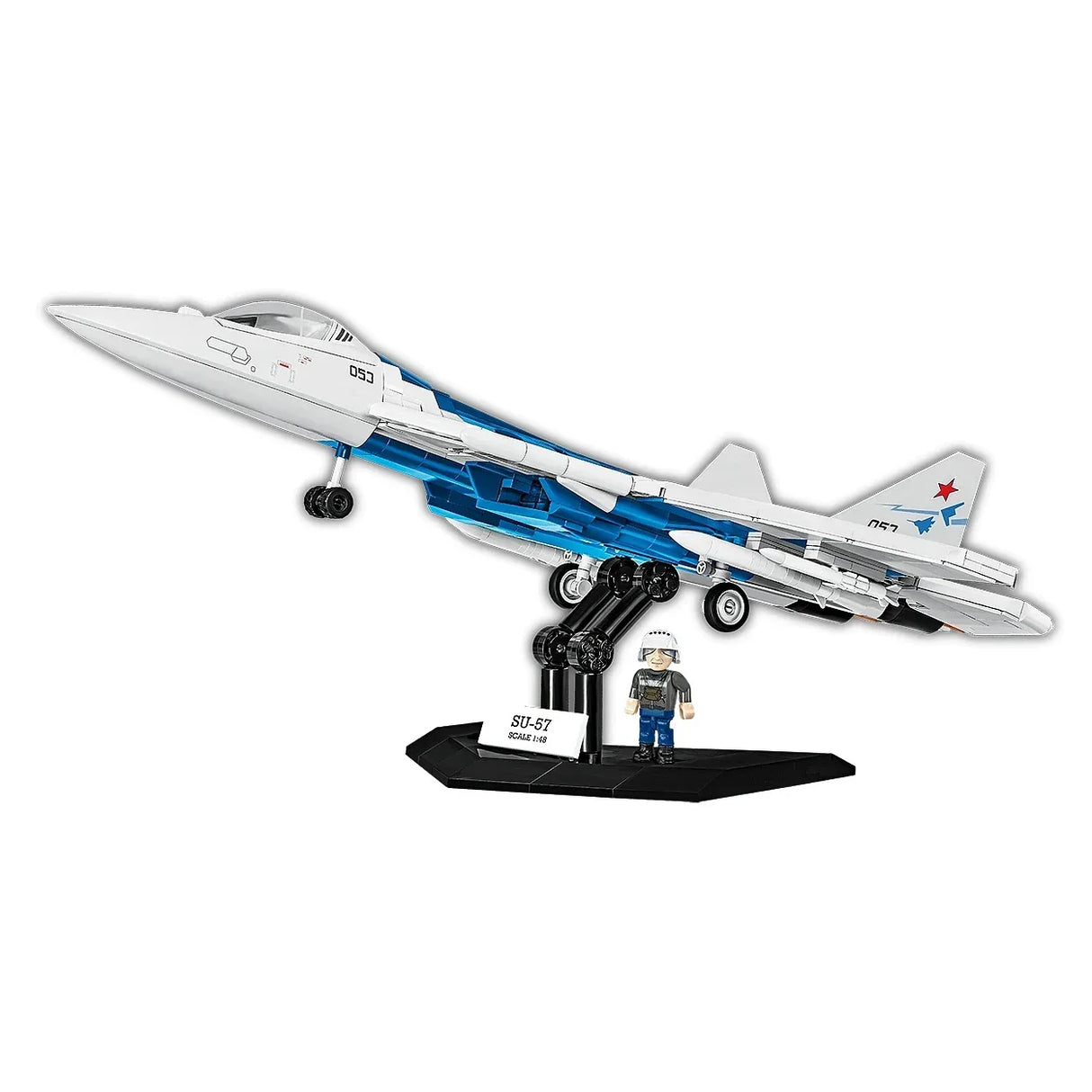 Modell eines weißen Kampfjets mit blauen Akzenten auf einem schwarzen Ständer, daneben eine kleine Pilotenfigur