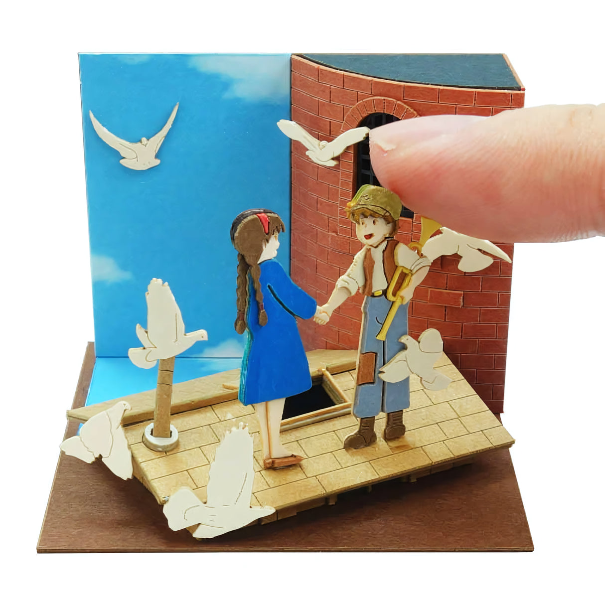 Miniatur-Diorama mit einem Mädchen und einem Jungen, die Händchen halten, umgeben von weißen Tauben