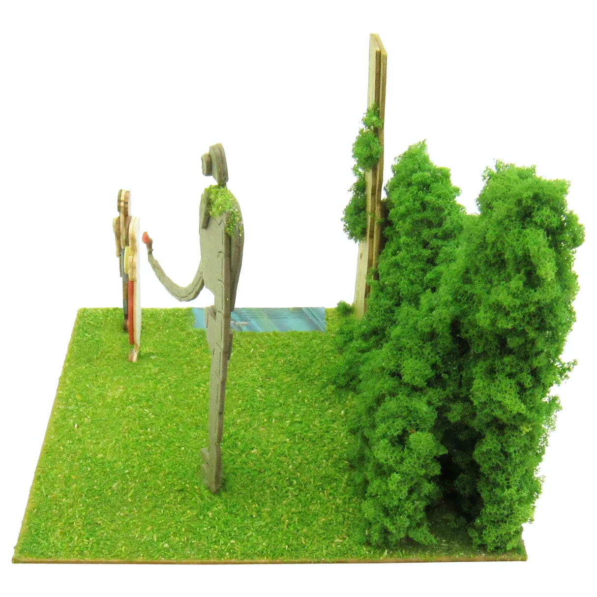 Modell einer Landschaft mit zwei Figuren, einem Baum und einem Busch auf grünem Gras