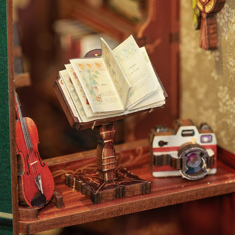 Miniatur-Geige, Notenständer mit offenem Buch und Kamera auf einem Holzregal