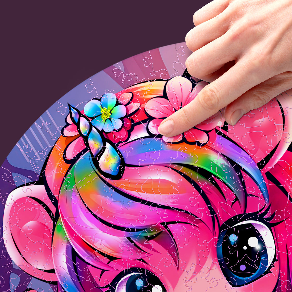 Hand platziert ein Puzzleteil auf einem bunten Einhorn-Puzzle mit Blumen im Haar