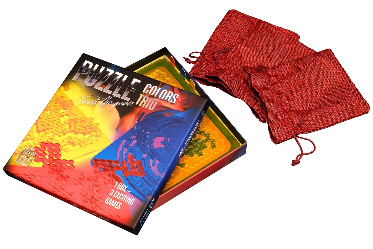 Geöffnete Puzzle Colors Trio Spielebox von ESC WELT mit den eingelegten Acryl-Puzzles und drei roten Stoffbeuteln zur Aufbewahrung.
