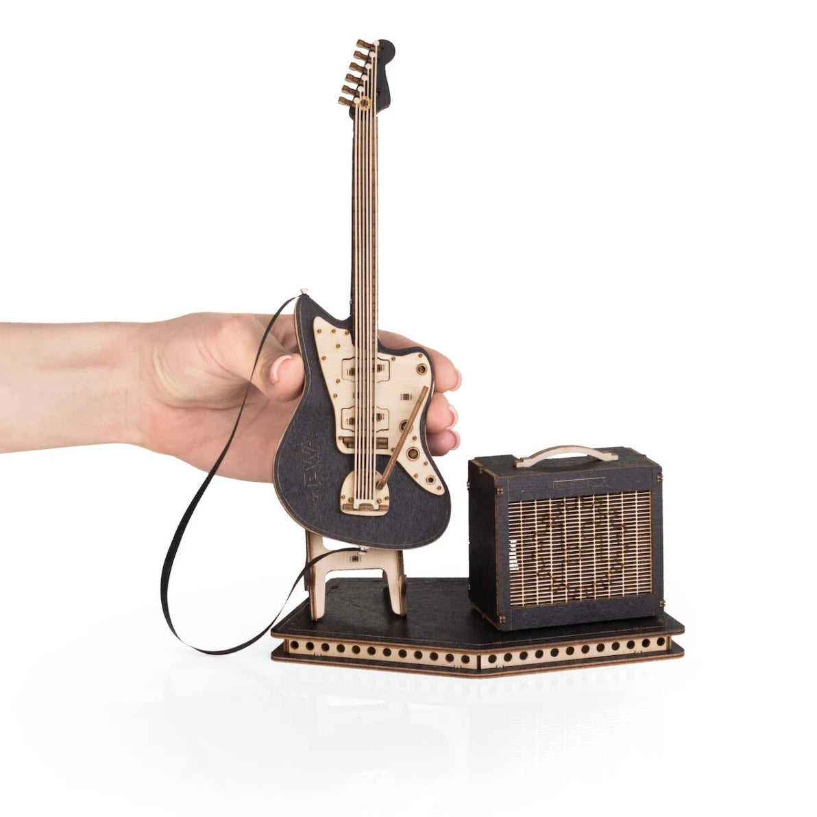 Eine Hand hält eine Miniatur-E-Gitarre aus Holz mit einem Verstärker auf einem Ständer