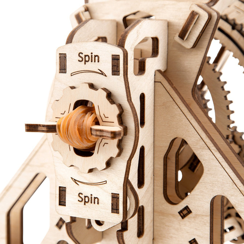 Nahaufnahme eines hölzernen Zahnradmechanismus mit der Aufschrift Spin und einem orangefarbenen Schneckengetriebe