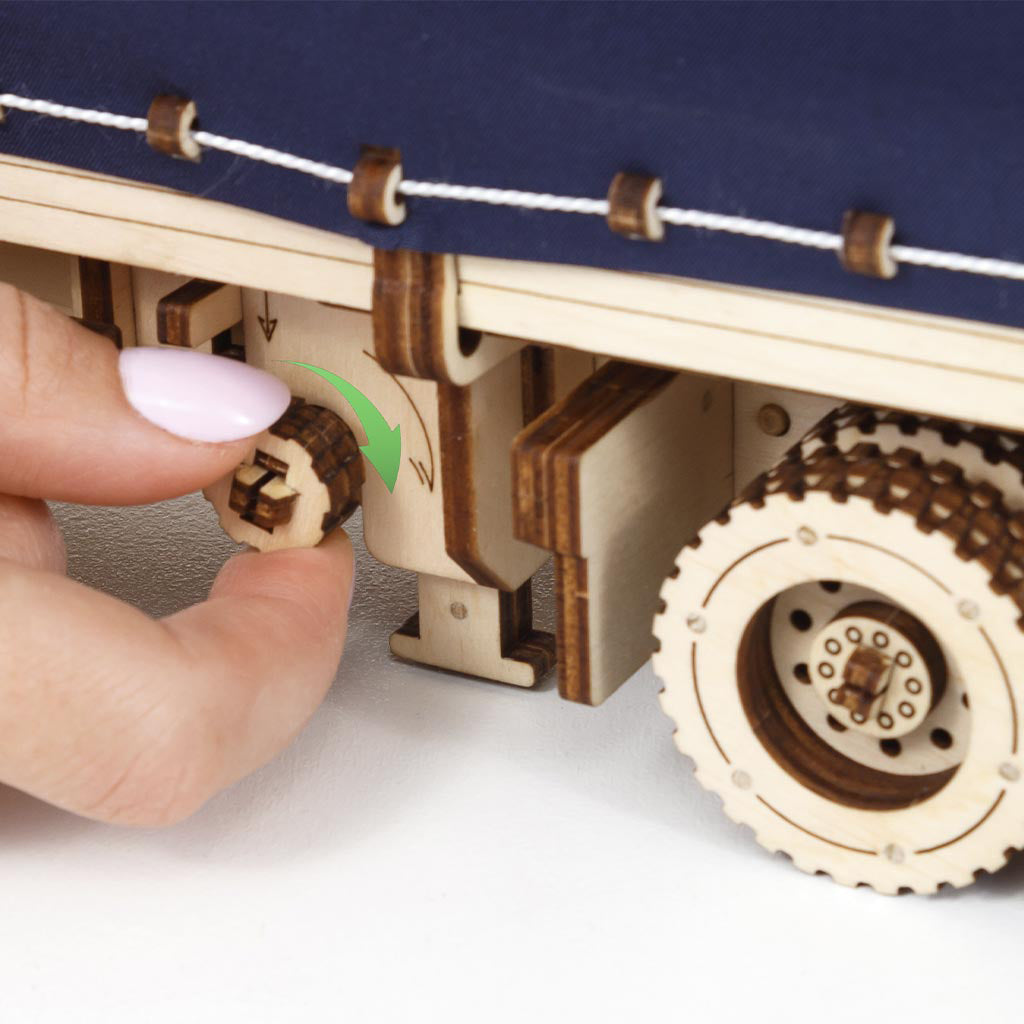Nahaufnahme einer Hand, die einen Holzmechanismus an einem Modell-LKW dreht