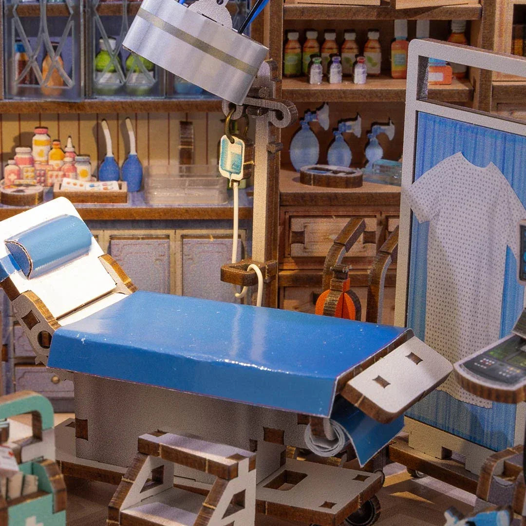 Miniatur-Krankenhauszimmer mit blauem Untersuchungsbett, Infusionsständer und medizinischen Geräten