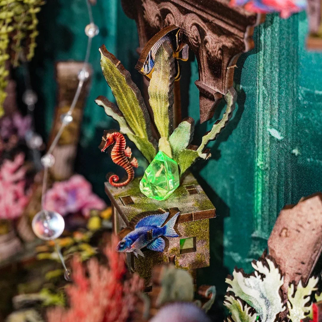 Miniatur-Unterwasserwelt mit Seepferdchen, Fischen, Pflanzen und einem leuchtenden grünen Kristall