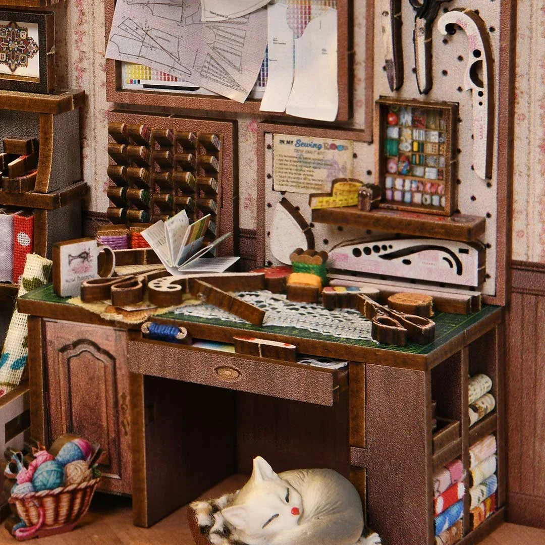 Miniatur-Nähzimmer mit Nähmaschine, Stoffen, Garnrollen und schlafender Katze