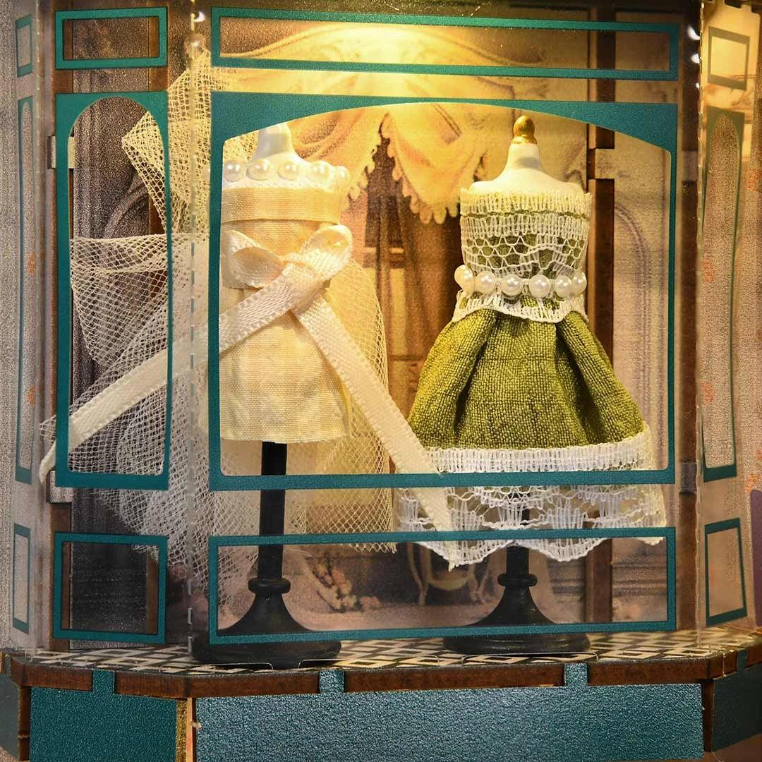 Zwei Schaufensterpuppen mit Kleidern in einem Miniatur-Schaufenster