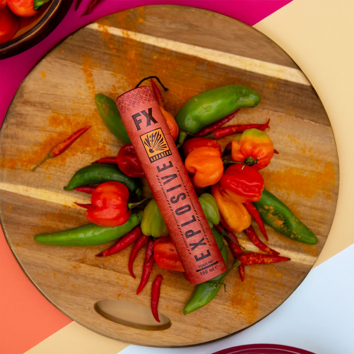 FX Explosive Habanero-Flasche auf Holzbrett mit verschiedenen Chilisorten