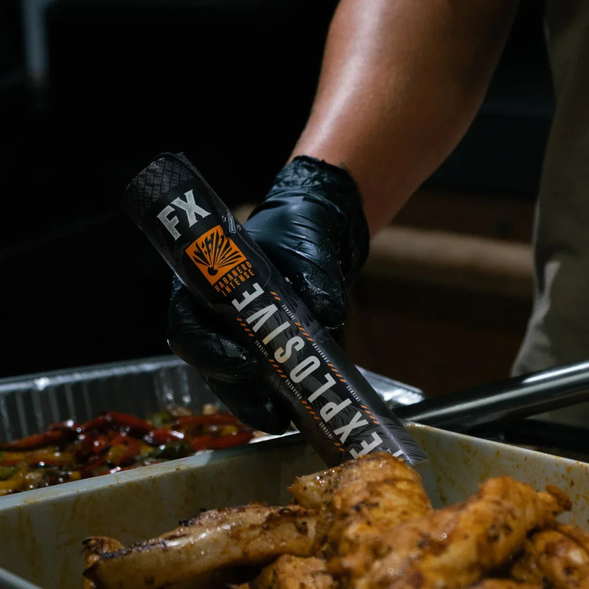 Hand in schwarzem Handschuh hält eine schwarze Flasche mit der Aufschrift FX Explosive Habanero Intense