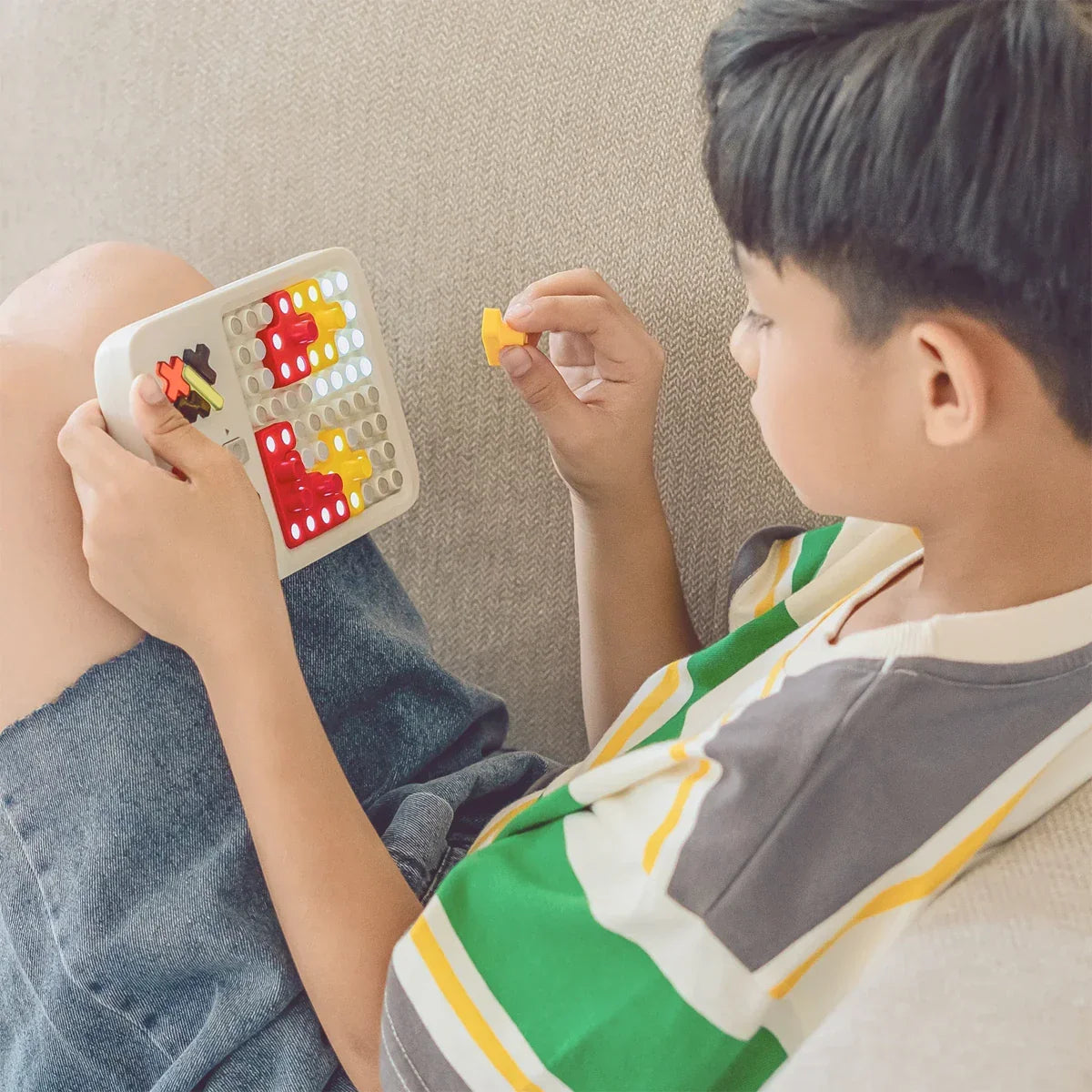 Kind spielt mit einem Puzzle-Spielzeug auf dem Sofa