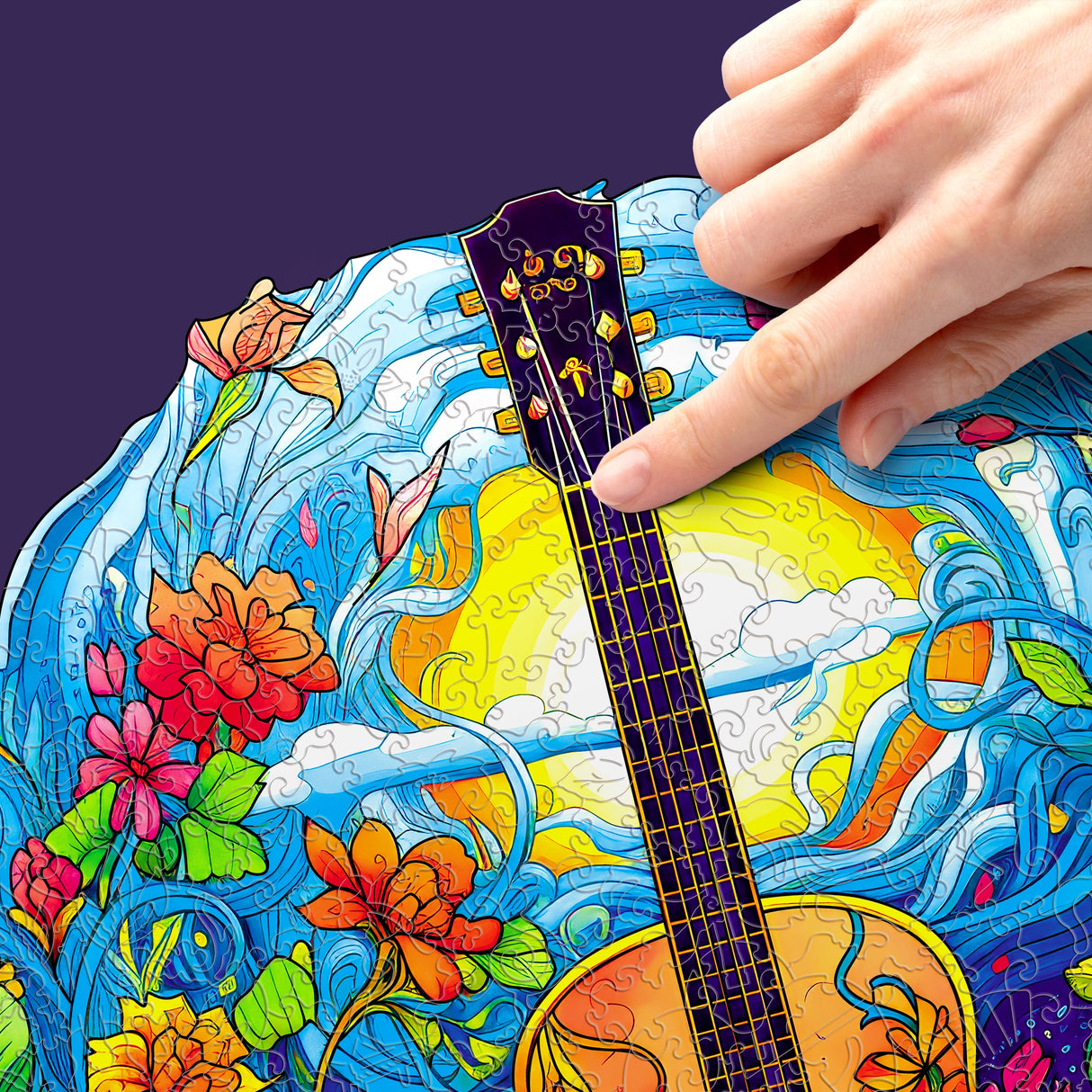 Eine Hand platziert ein Puzzleteil auf einem bunten Puzzle mit Gitarre, Blumen und Sonne