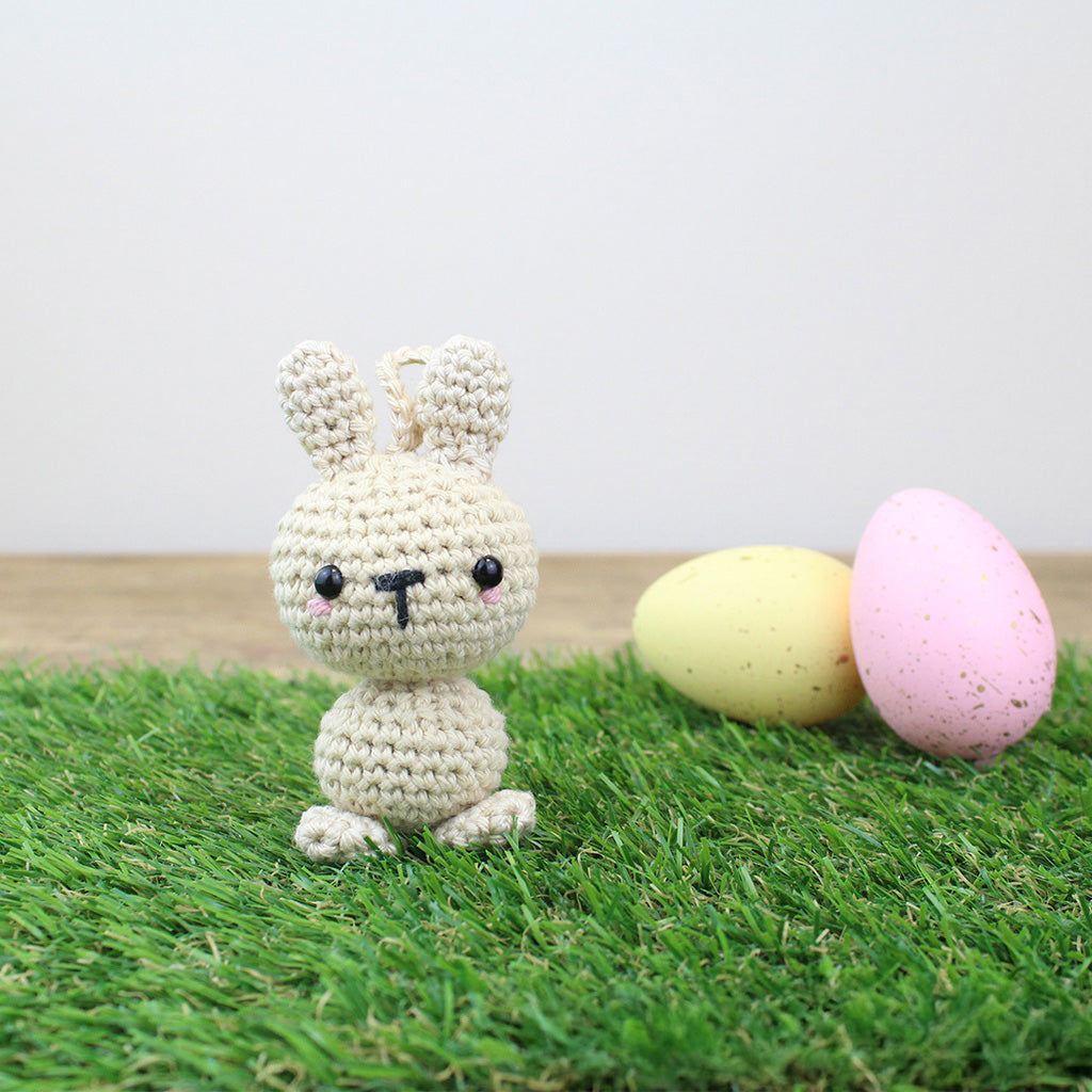 Gehäkelter Hase mit zwei Ostereiern auf grünem Gras