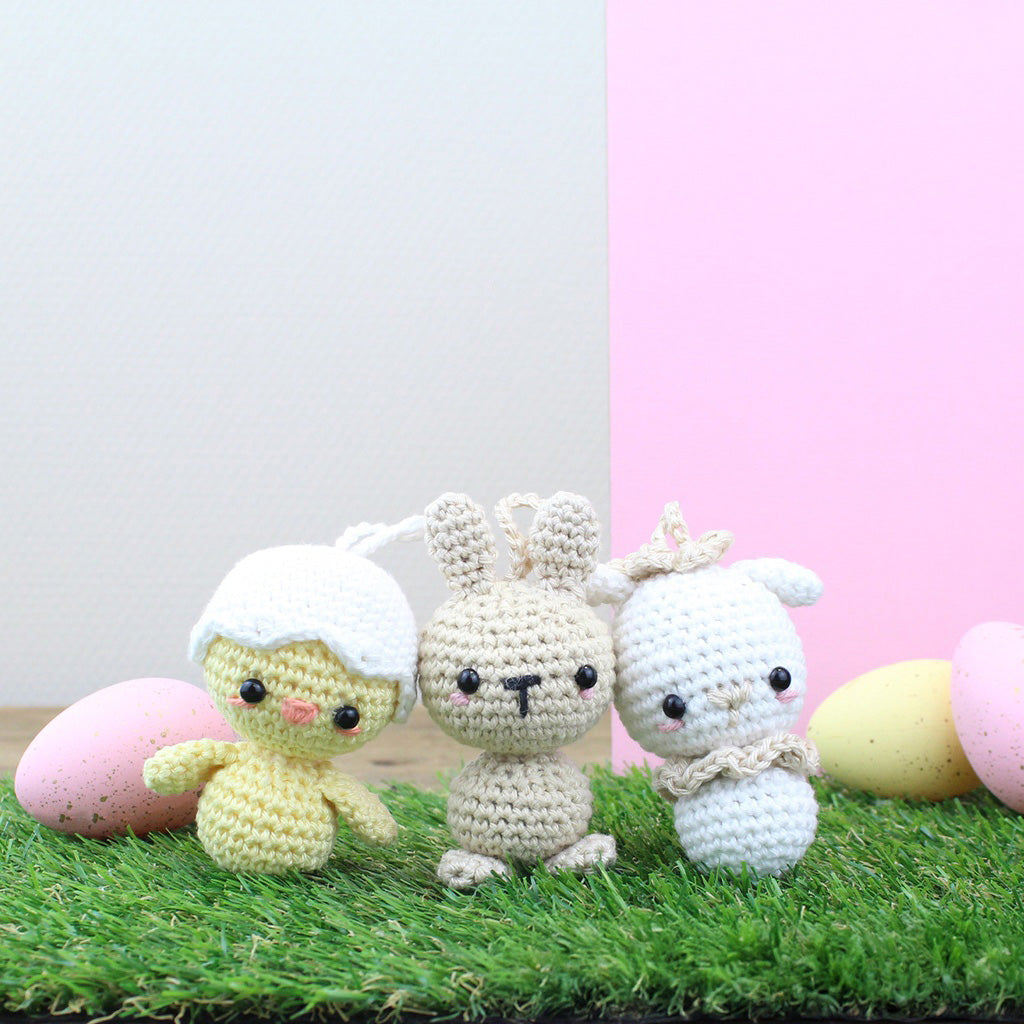 Gehäkelte Osterfiguren: Küken, Hase und Lamm auf Gras mit Ostereiern