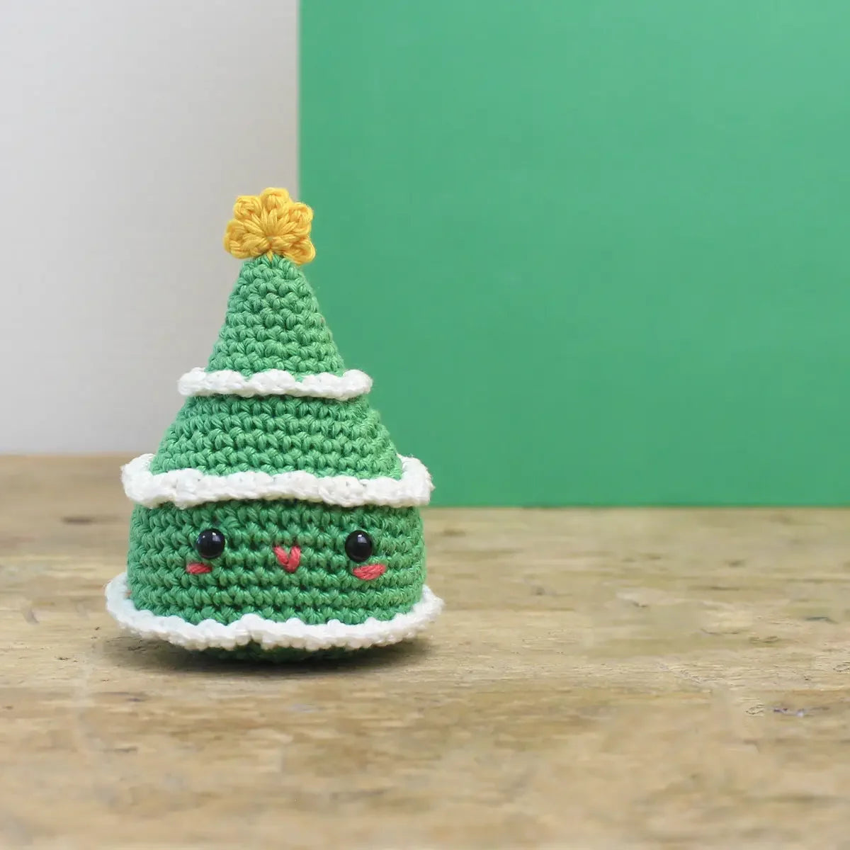 Gehäkelter Weihnachtsbaum mit Gesicht auf einem Holztisch