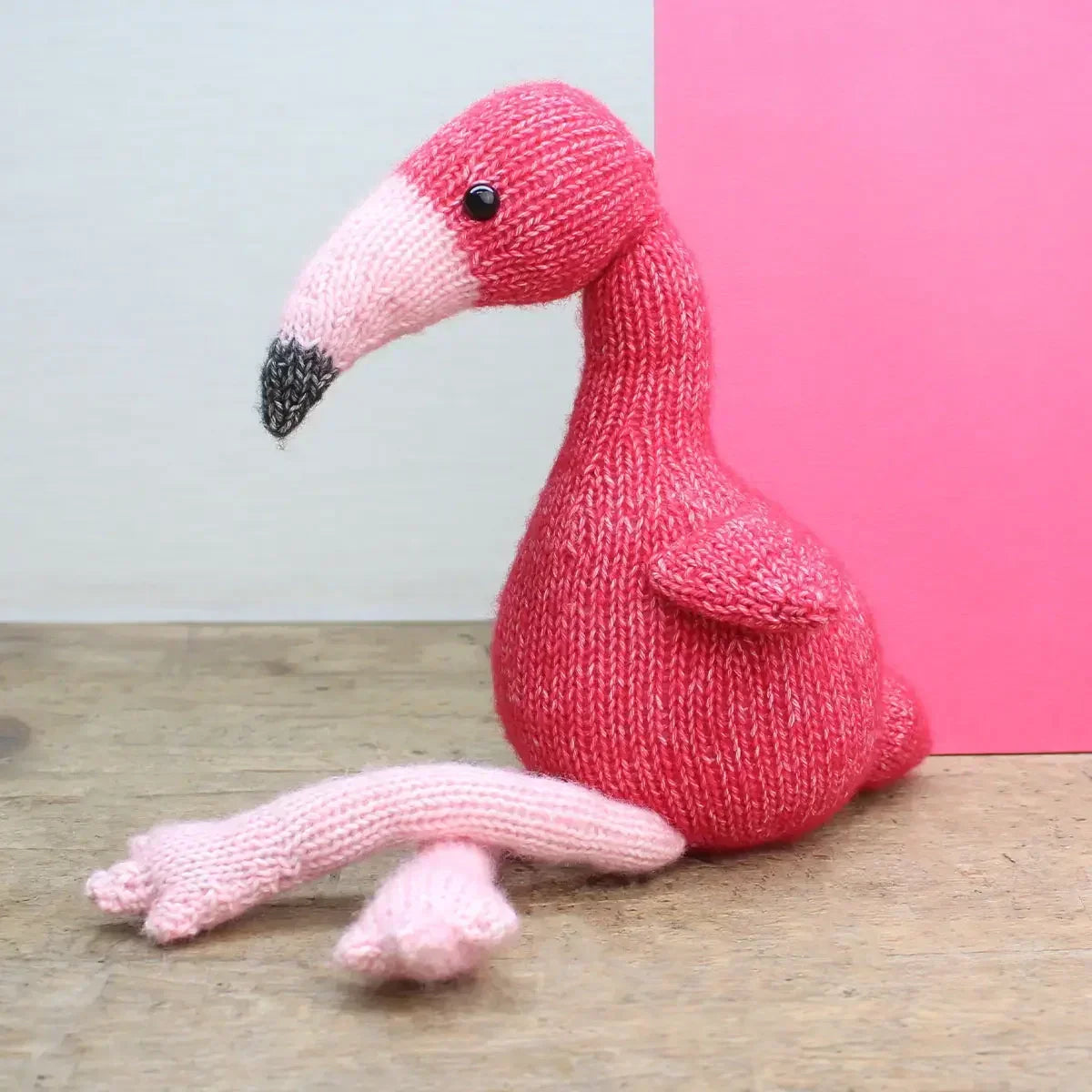 Gestrickte Flamingo Figur in Pink auf einem Holztisch