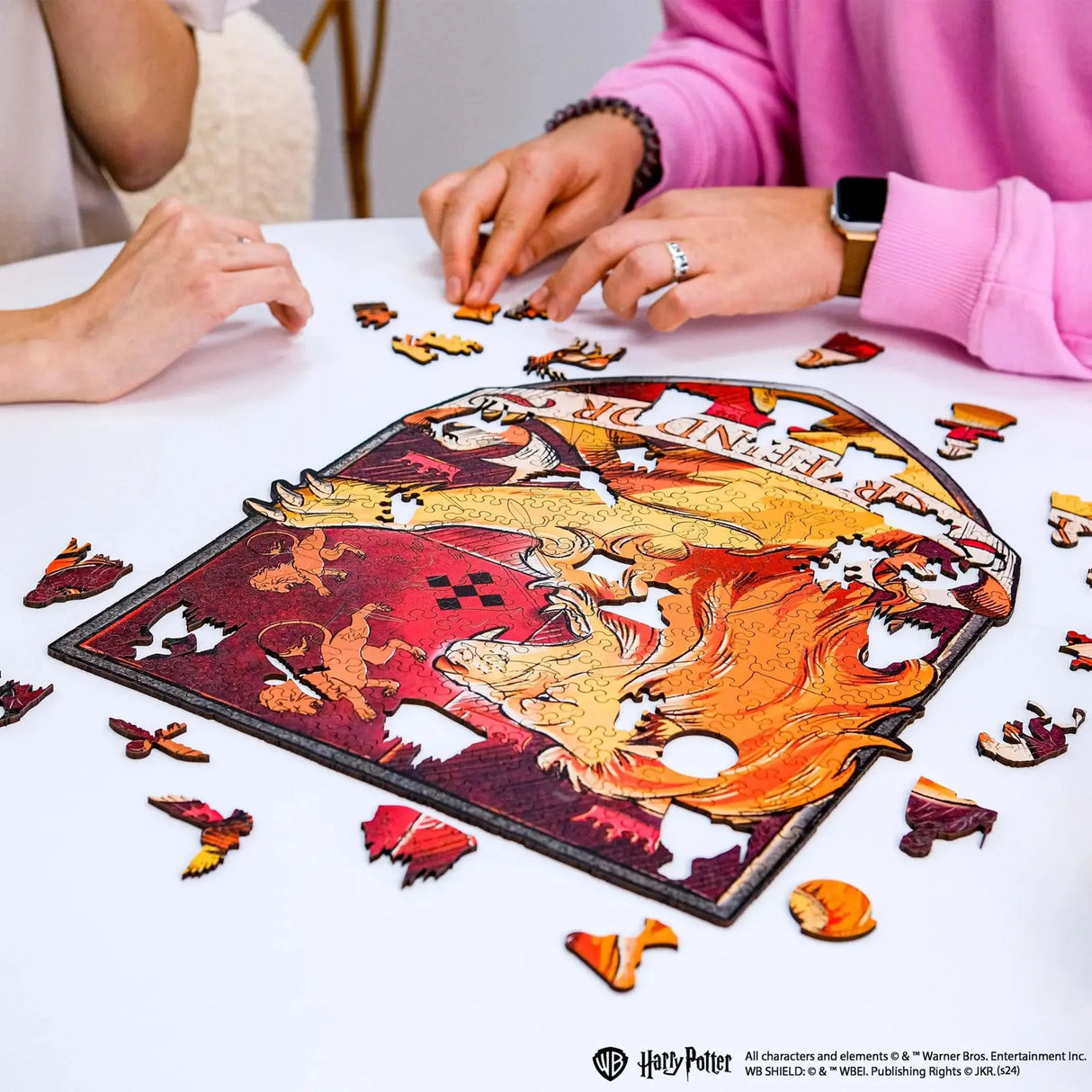 Zwei Personen legen ein Harry Potter Puzzle mit einem Phönix und einem Löwen