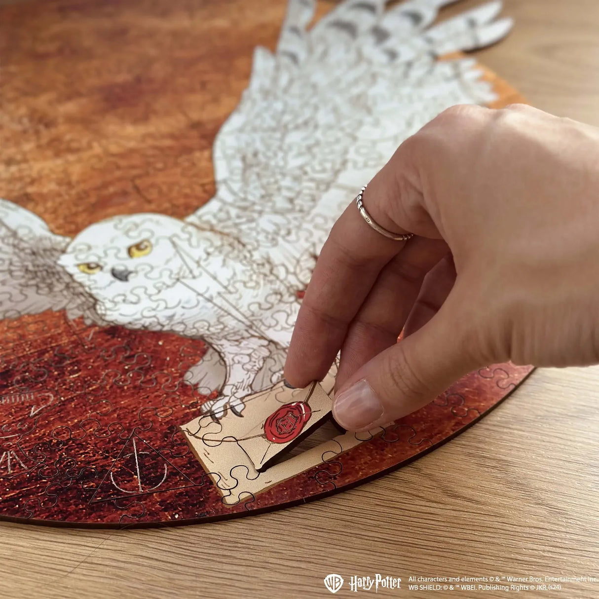 Hand platziert ein Puzzleteil mit einem Brief mit rotem Siegel auf einem Harry Potter Eulenpuzzle