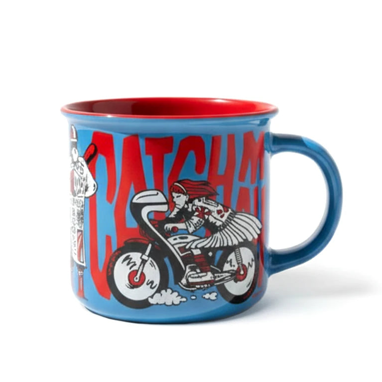 Blaue Tasse mit rotem Rand und Griff, darauf eine Frau auf einem Motorrad und roter Text