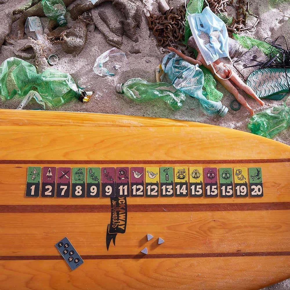 Surfbrett mit Spielkarten und Müll am Strand