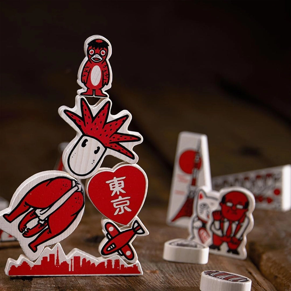 Holzfiguren in Rot und Weiß, die einen Turm bilden, mit einem Flugzeug und einem Herzen mit der Aufschrift Tokio
