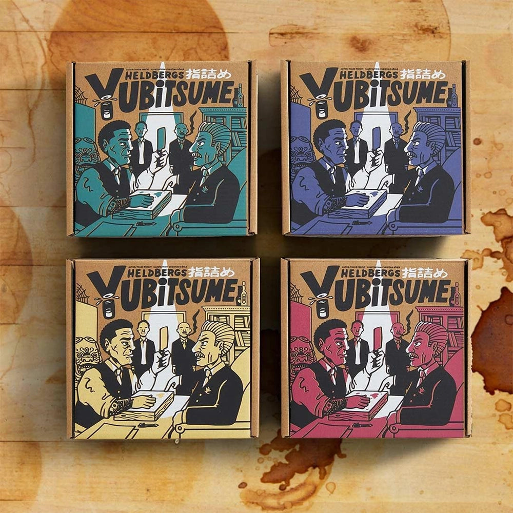 Vier Heldbergs Yubitsume Schachteln in verschiedenen Farben auf einem Holztisch mit Kaffeeflecken