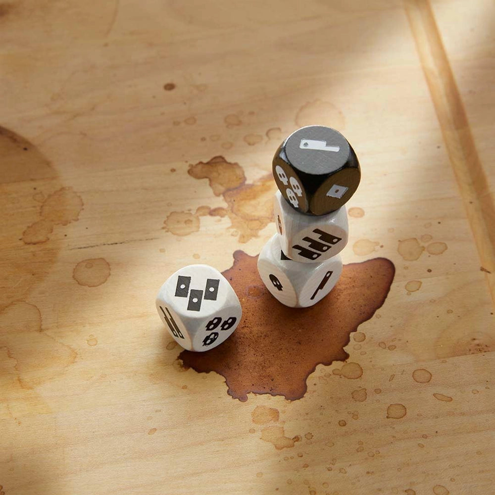 Drei weiße und ein schwarzer Würfel mit Symbolen auf einem Holztisch mit Kaffeeflecken