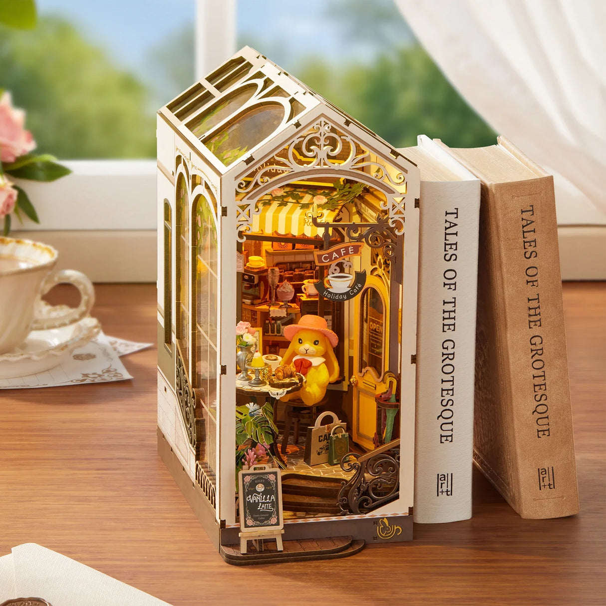 Miniatur-Café-Diorama mit einem Hasen, der an einem Tisch sitzt, neben zwei Büchern auf einem Holztisch
