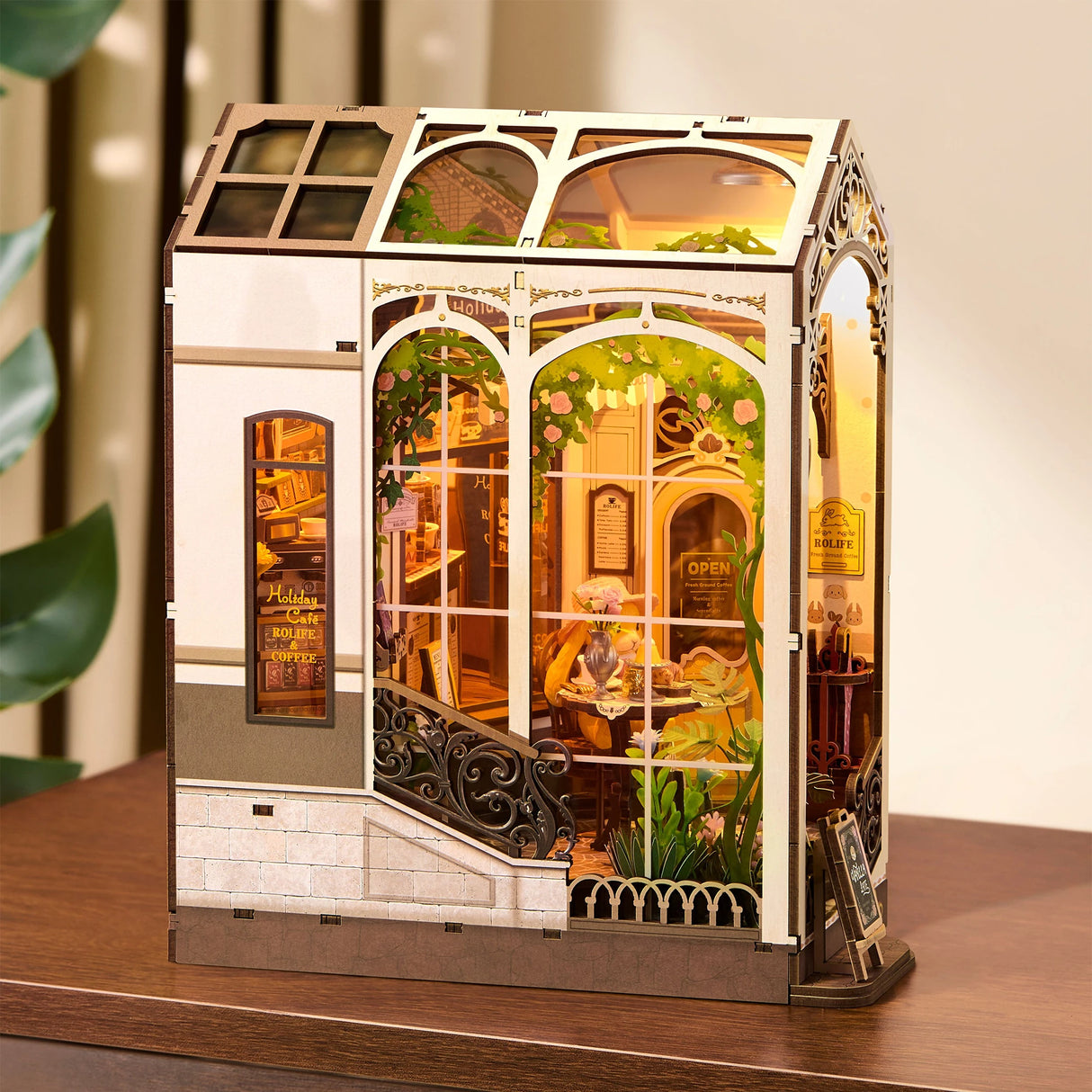 Miniatur-Diorama eines Cafés mit großen Fenstern, die den Innenraum mit Tischen, Stühlen und Pflanzen zeigen