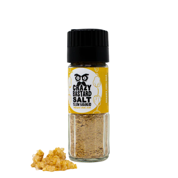 Crazy Bastard Salt Yellow Habanero Gewürzstreuer mit gelbem Etikett und Haufen Salz daneben