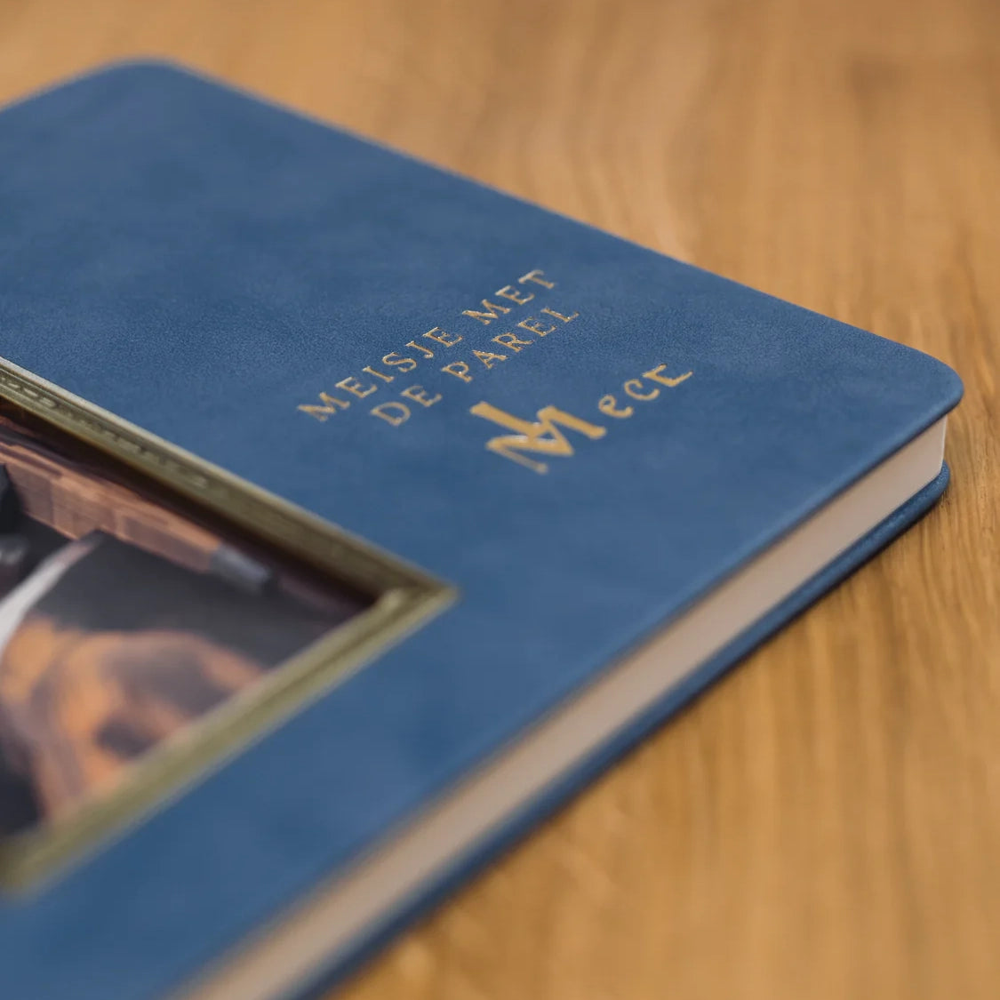 Nahaufnahme eines blauen Notizbuchs mit goldener Schrift und einem Bildausschnitt