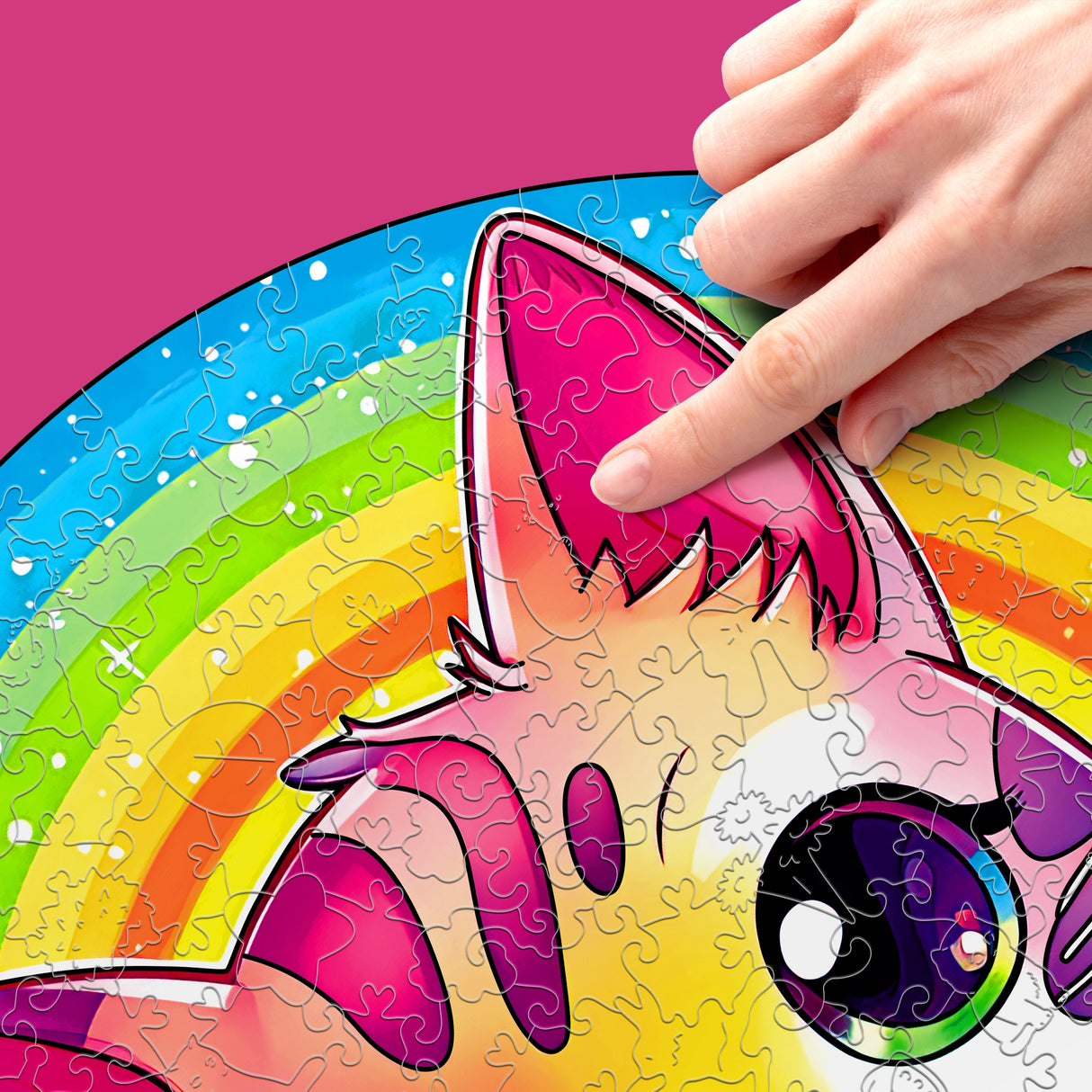 Hand platziert Puzzleteil auf einem Einhorn-Puzzle mit Regenbogenhintergrund