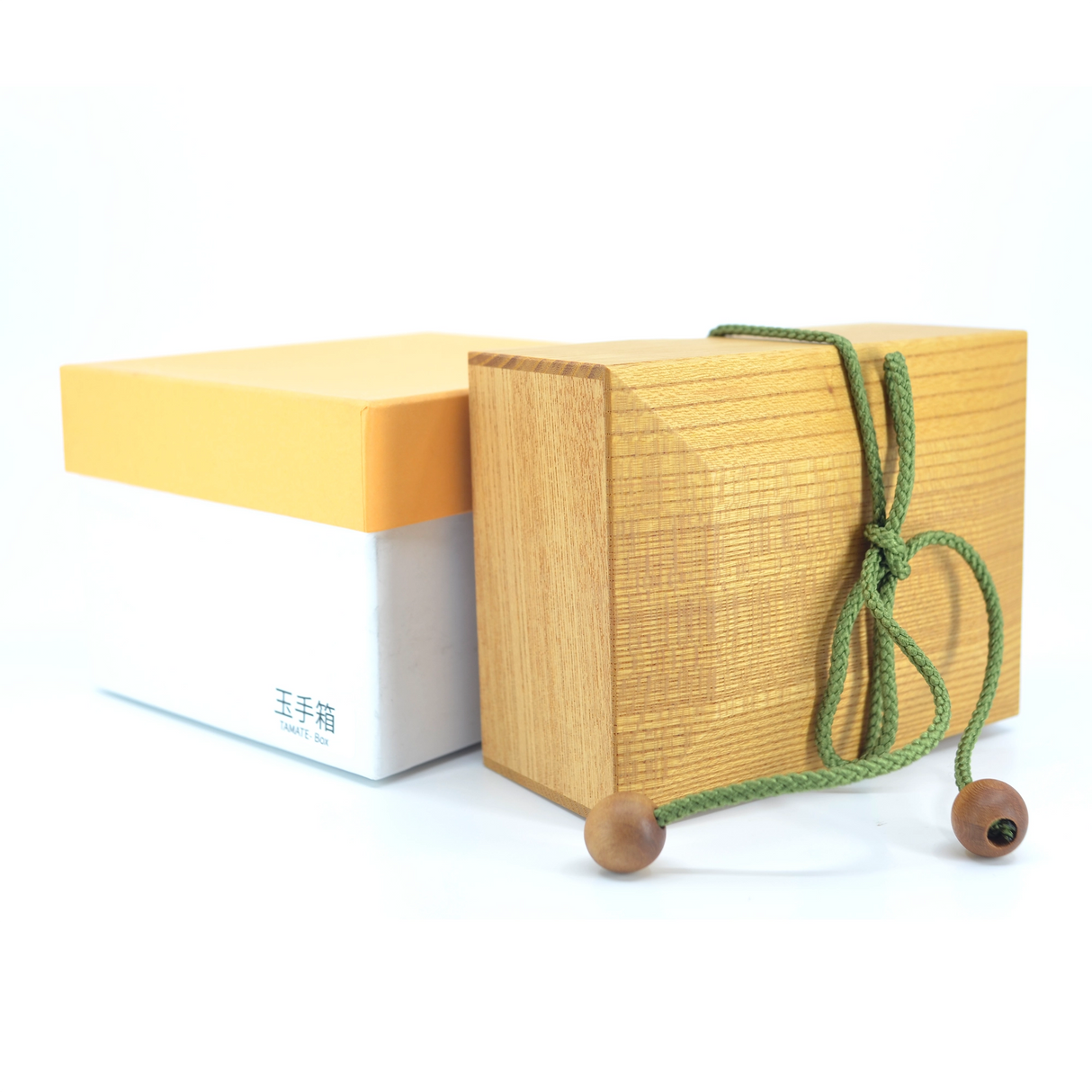 Holzschatulle mit gruener Kordel neben einer weiss gelben Geschenkbox