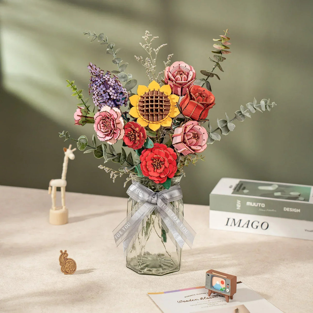 Bunter Blumenstrauß aus Holzbauteilen in einer Glasvase mit Schleife auf einem Tisch