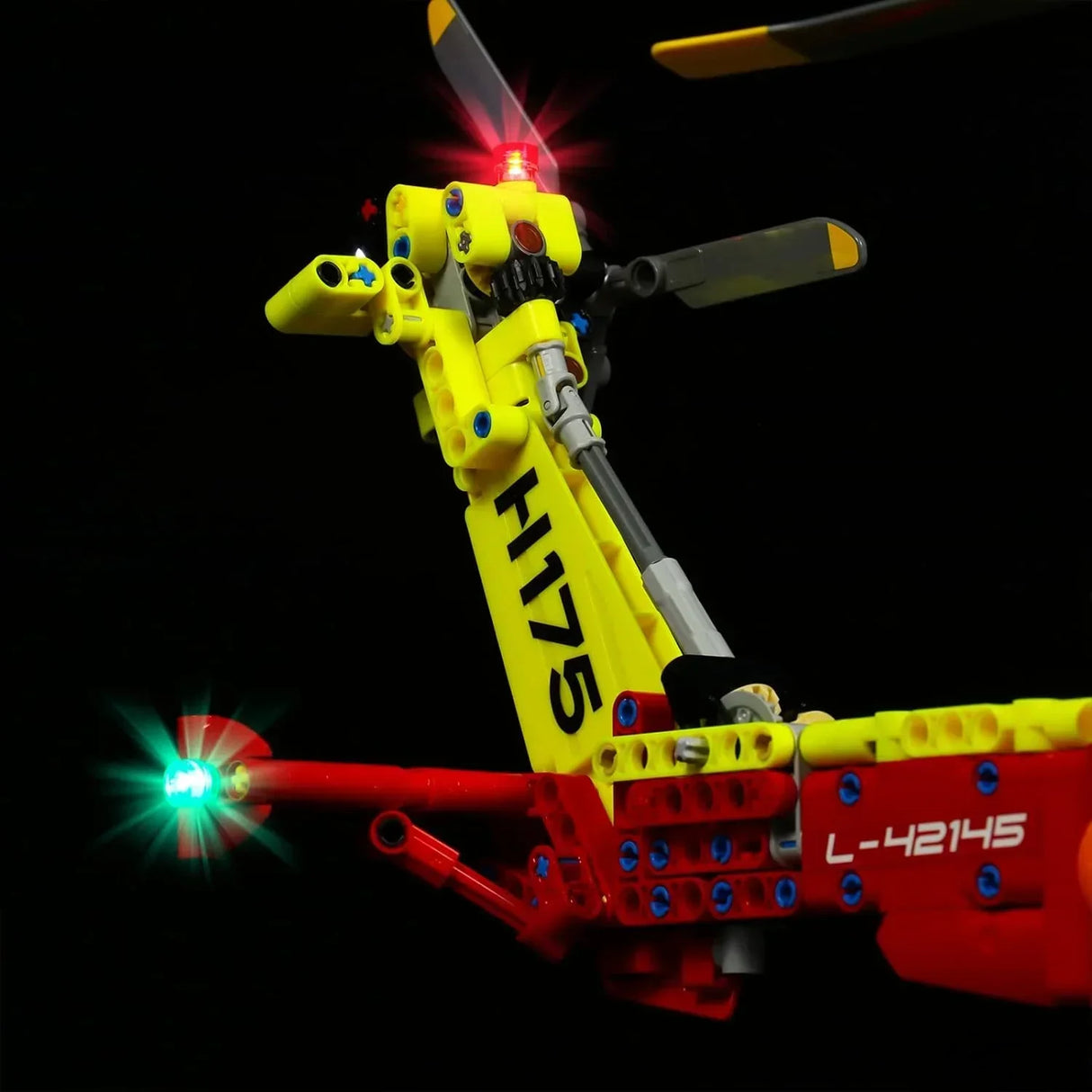 Beleuchtetes Heck eines gelb roten Lego Hubschraubers vor schwarzem Hintergrund