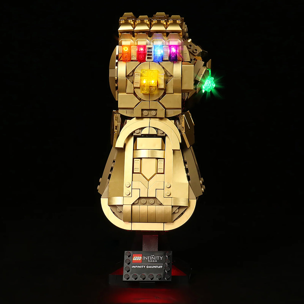 Beleuchteter goldener Infinity Handschuh aus Lego Steinen auf einem schwarzen Sockel