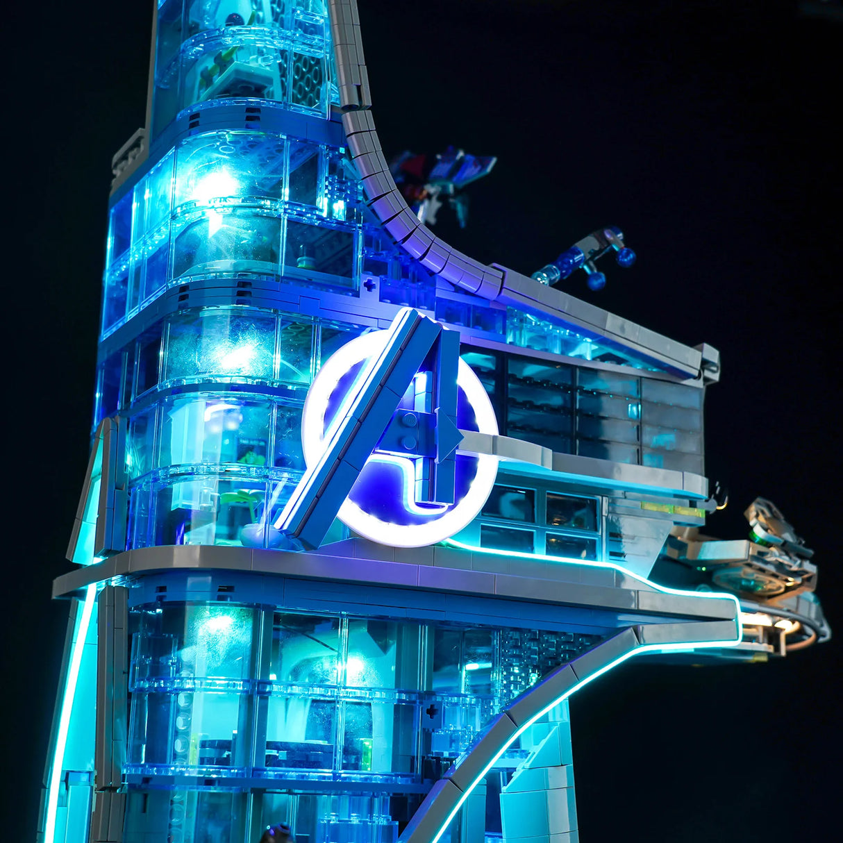 Beleuchtetes Avengers Tower Modell aus Klemmbausteinen mit blauem Leuchten vor dunklem Hintergrund