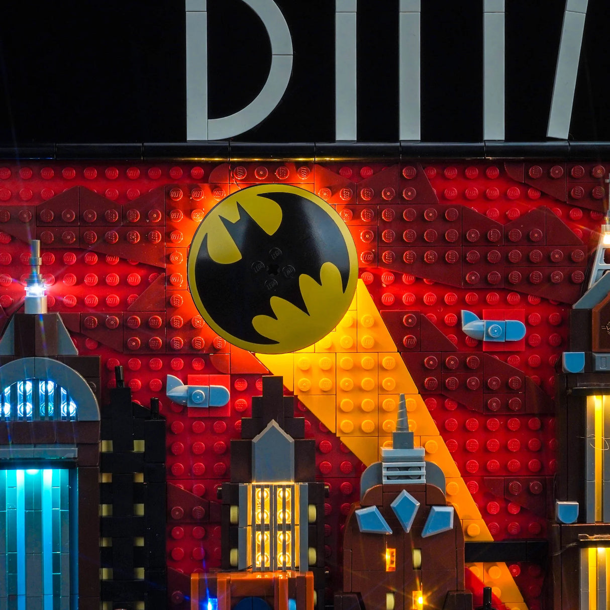 Beleuchtetes Lego Batman Wandbild mit Skyline und Bat-Signal vor rotem Hintergrund