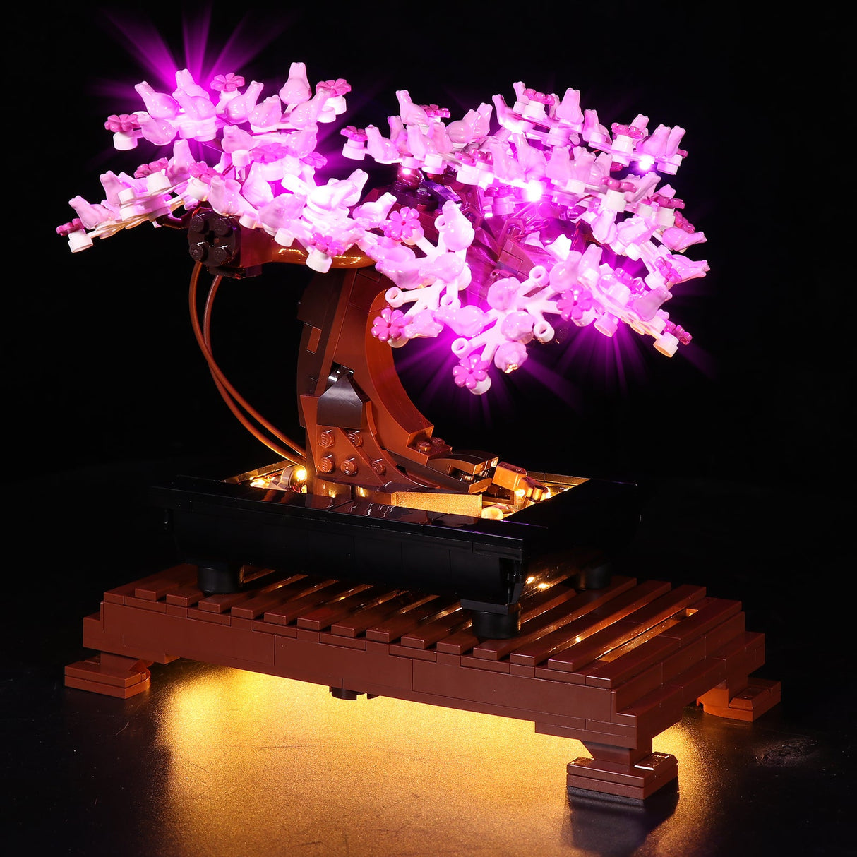 LEGO Creator Expert Bonsai Baum Set 10281 in der Frühlings-Version mit rosa Blüten, effektvoll in Szene gesetzt durch integrierte LED-Beleuchtung auf einem braunen Präsentationsständer.