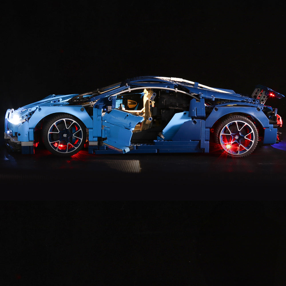 Blaues Bugatti Modellauto aus Klemmbausteinen mit eingeschalteter LED Beleuchtung vor schwarzem Hintergrund