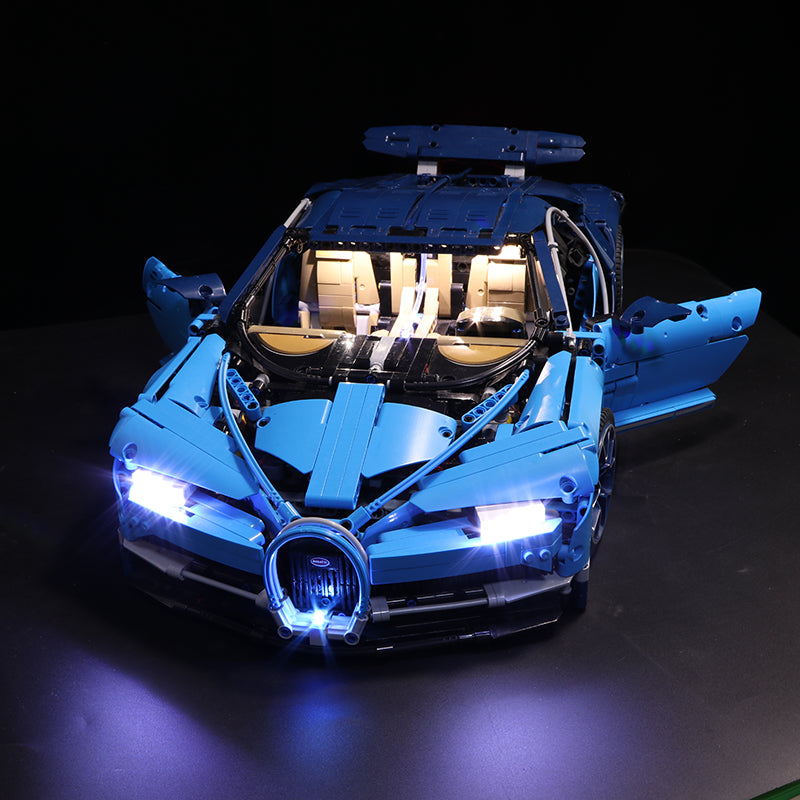 Blaues Lego Technic Modell eines Sportwagens mit eingeschalteter LED Beleuchtung vor schwarzem Hintergrund