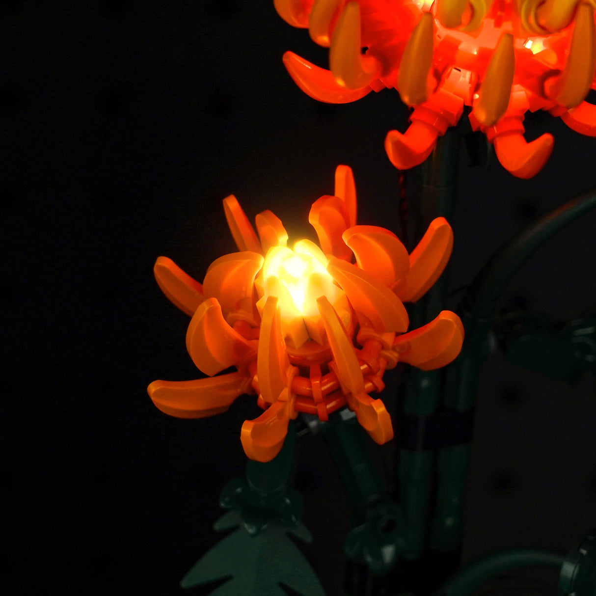 Beleuchtete orangefarbene Lego Blume vor schwarzem Hintergrund