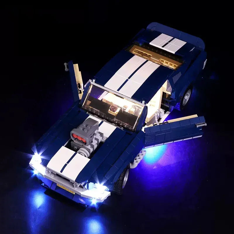 Blaues Lego Modellauto mit weissen Streifen und eingeschalteter LED Beleuchtung vor schwarzem Hintergrund